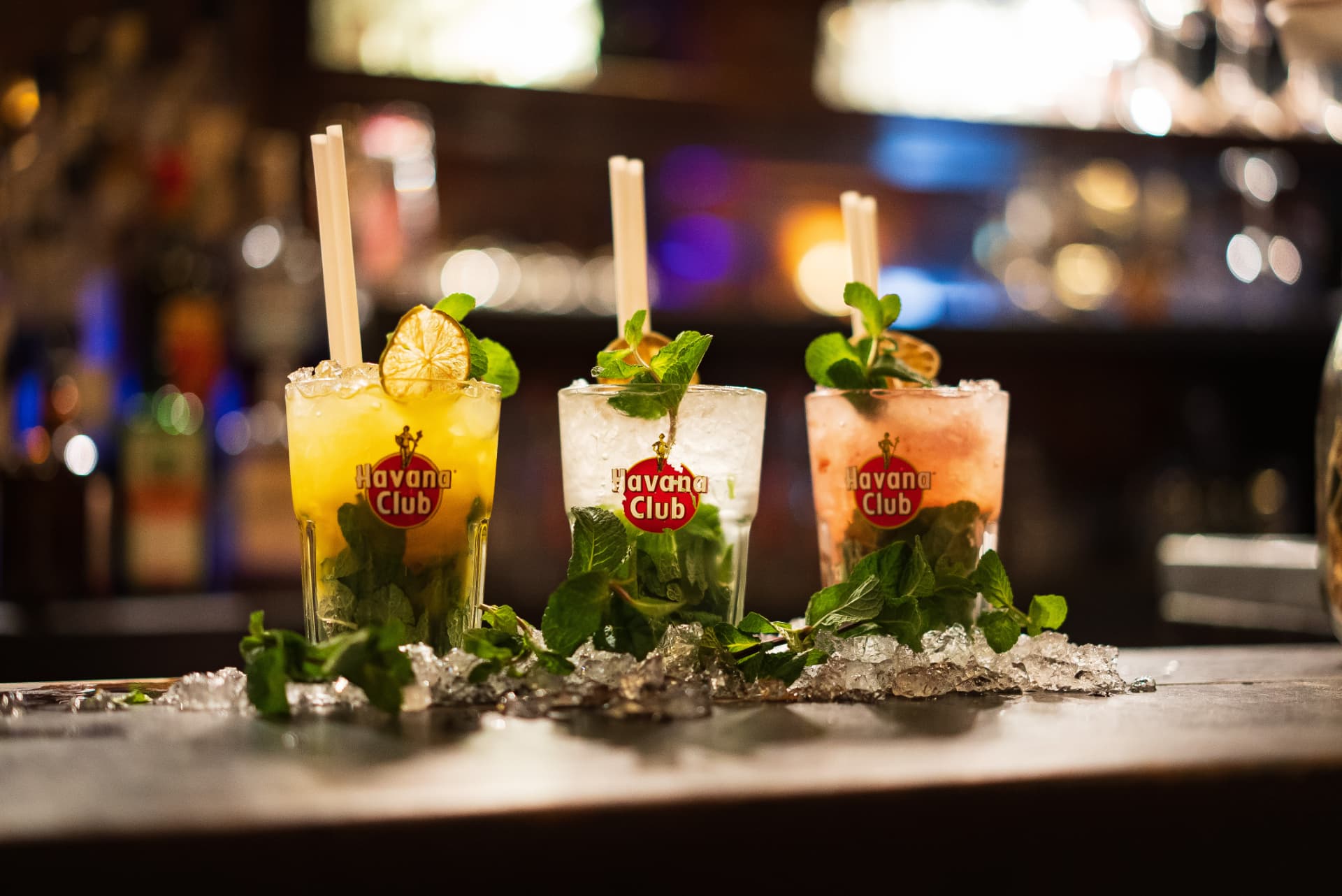 Trois mojitos colorés alignés sur le comptoir du bar