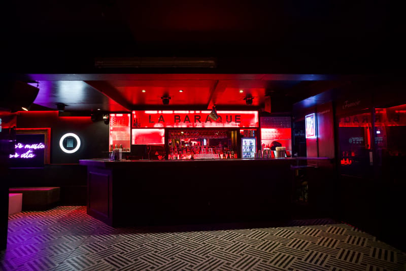 Bar du club éclairé en rouge et violet avant l'arrivée des invités