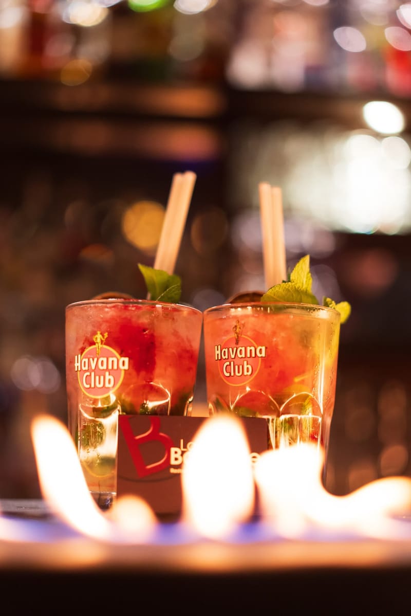 Deux mojitos servis derrière une ligne de flammes sur le bar