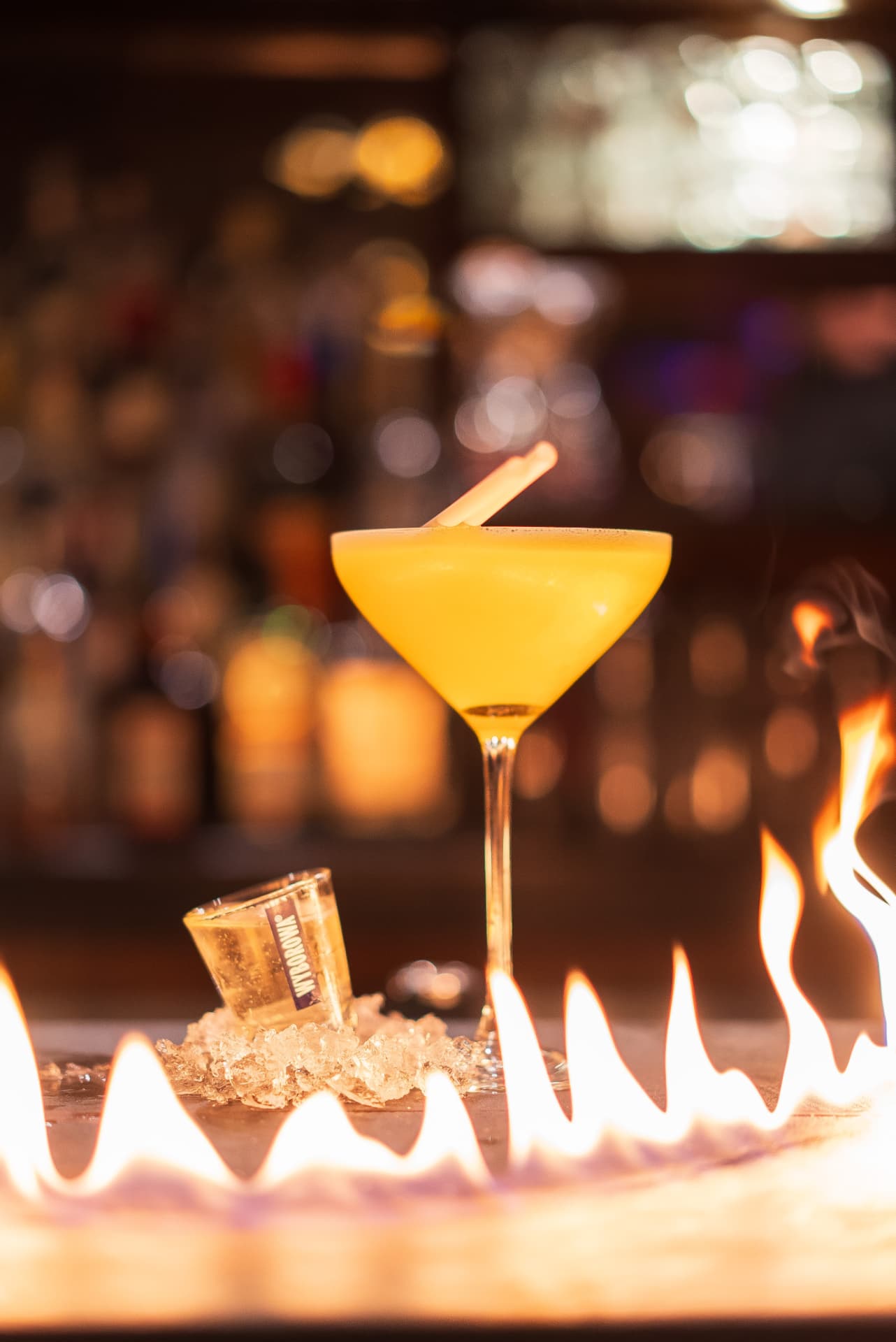 Cocktail jaune et shot devant un rideau de flammes
