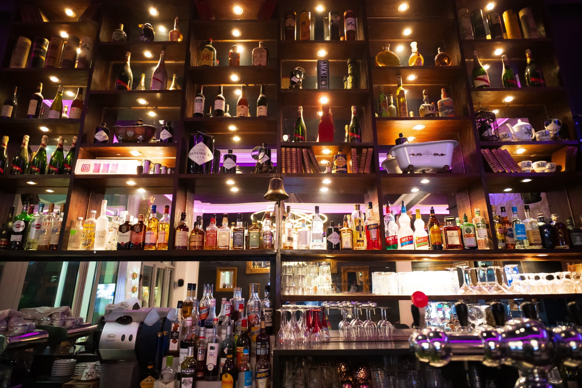 Étagères de bouteilles éclairées derrière le bar de La Baraque